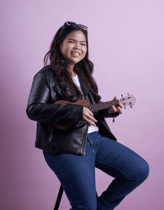Joanna Hioe smiling with a guitar